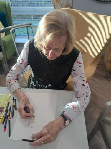 Resident concentrating on sketching during an art session at Boclair Care Home