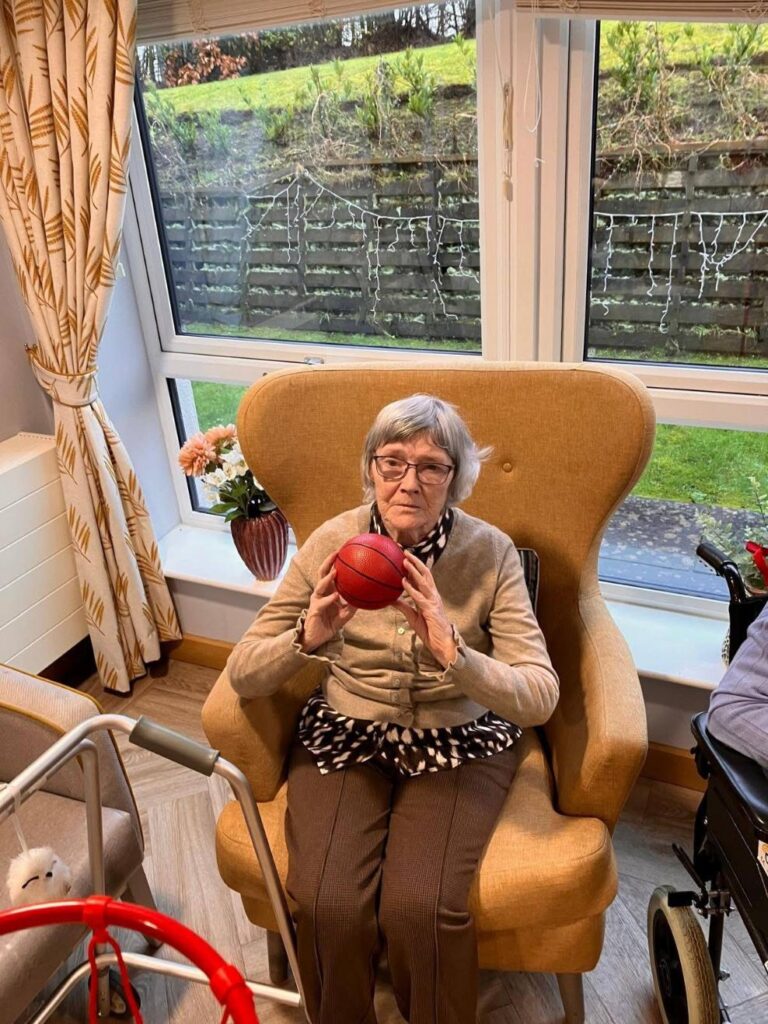 elderly woman throwing mini basketball into indoor hoop
