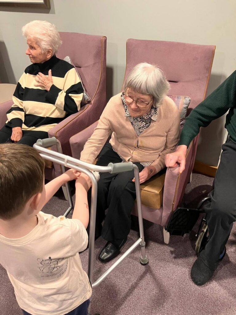 elderly woman with walking frame greets a child