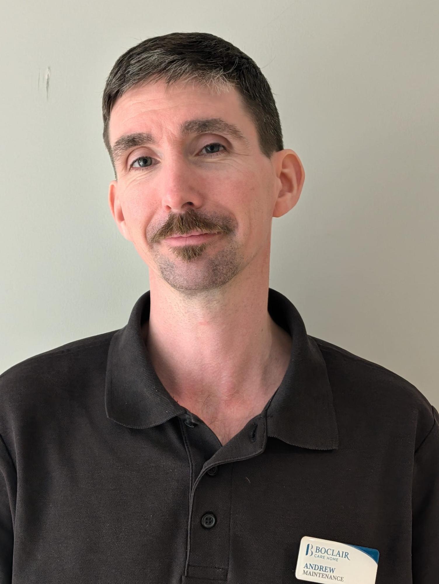 man in black polo shirt against white backdrop