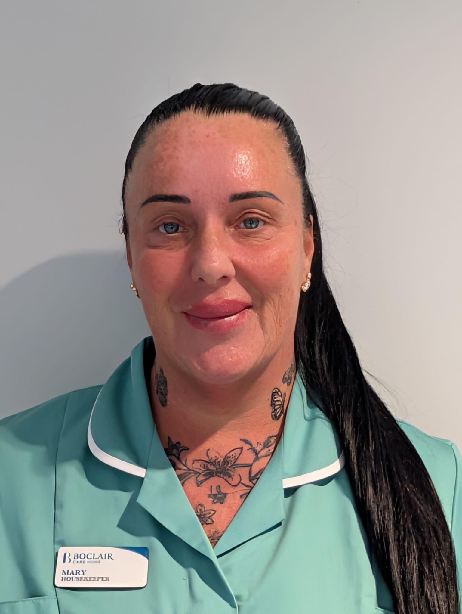 care home housekeeper with dark hair in turquoise uniform