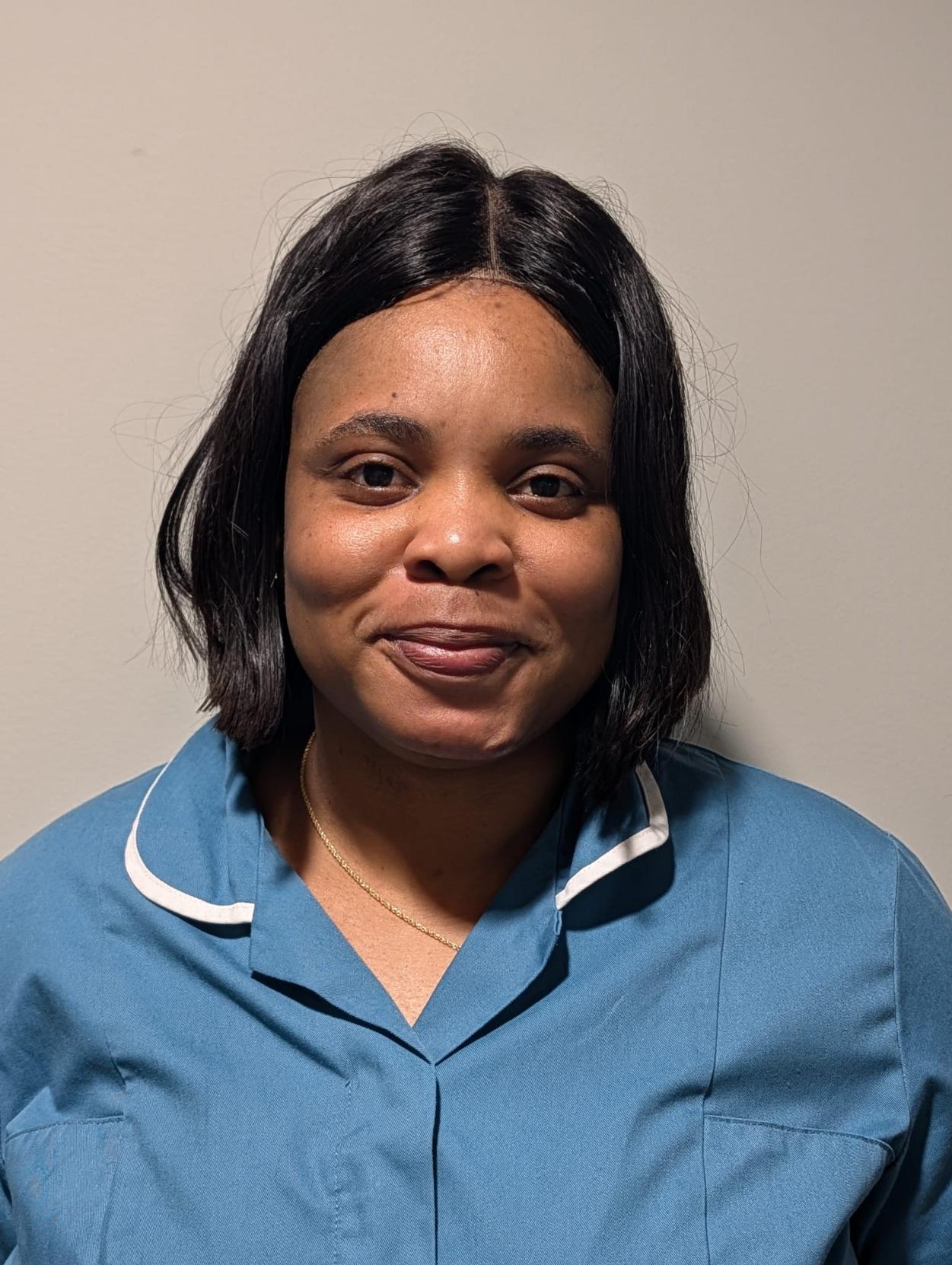 care assistant with short black hair wearing a light blue nurses uniform