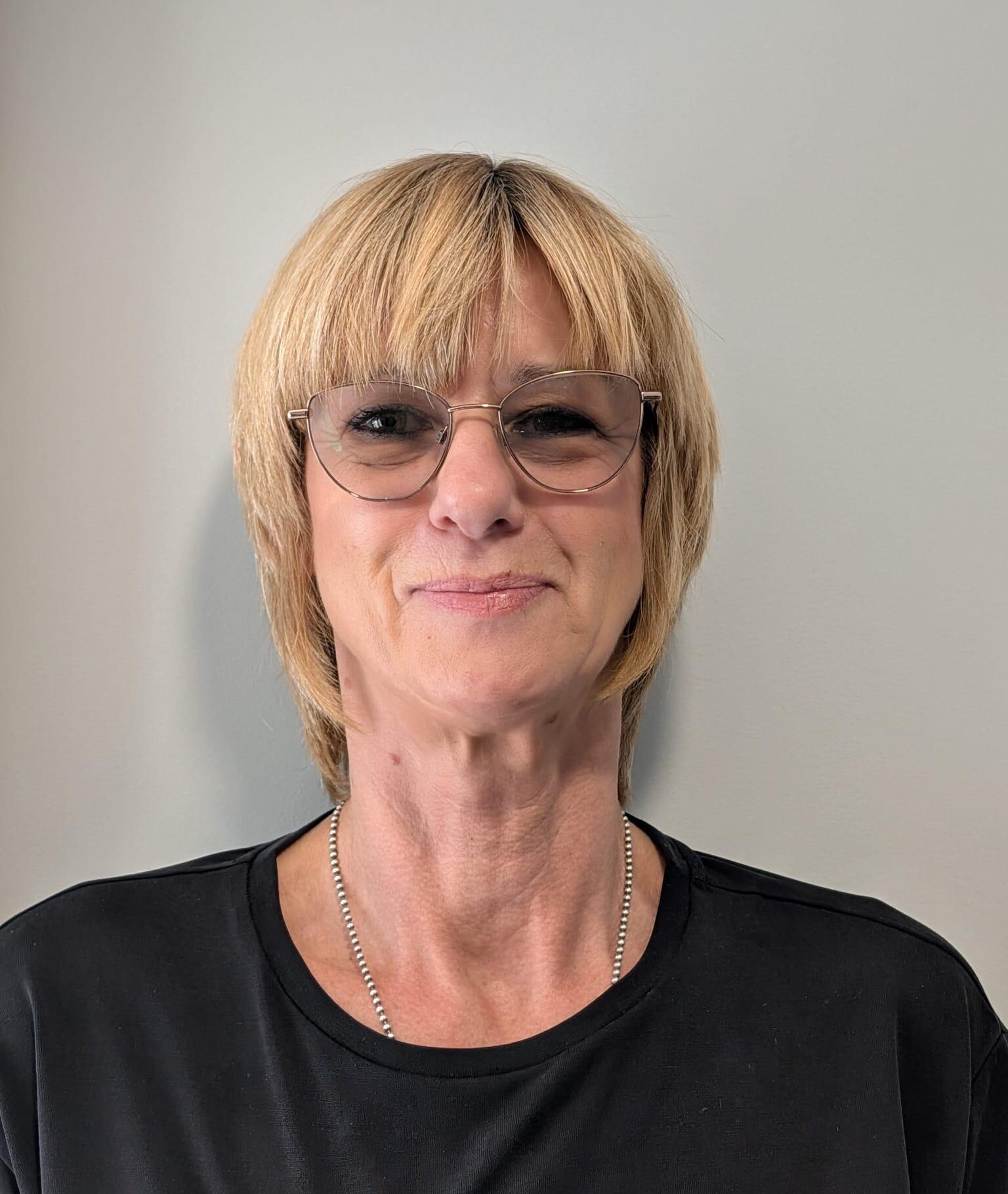 woman with short blonde hair and glasses and a black t-shirt