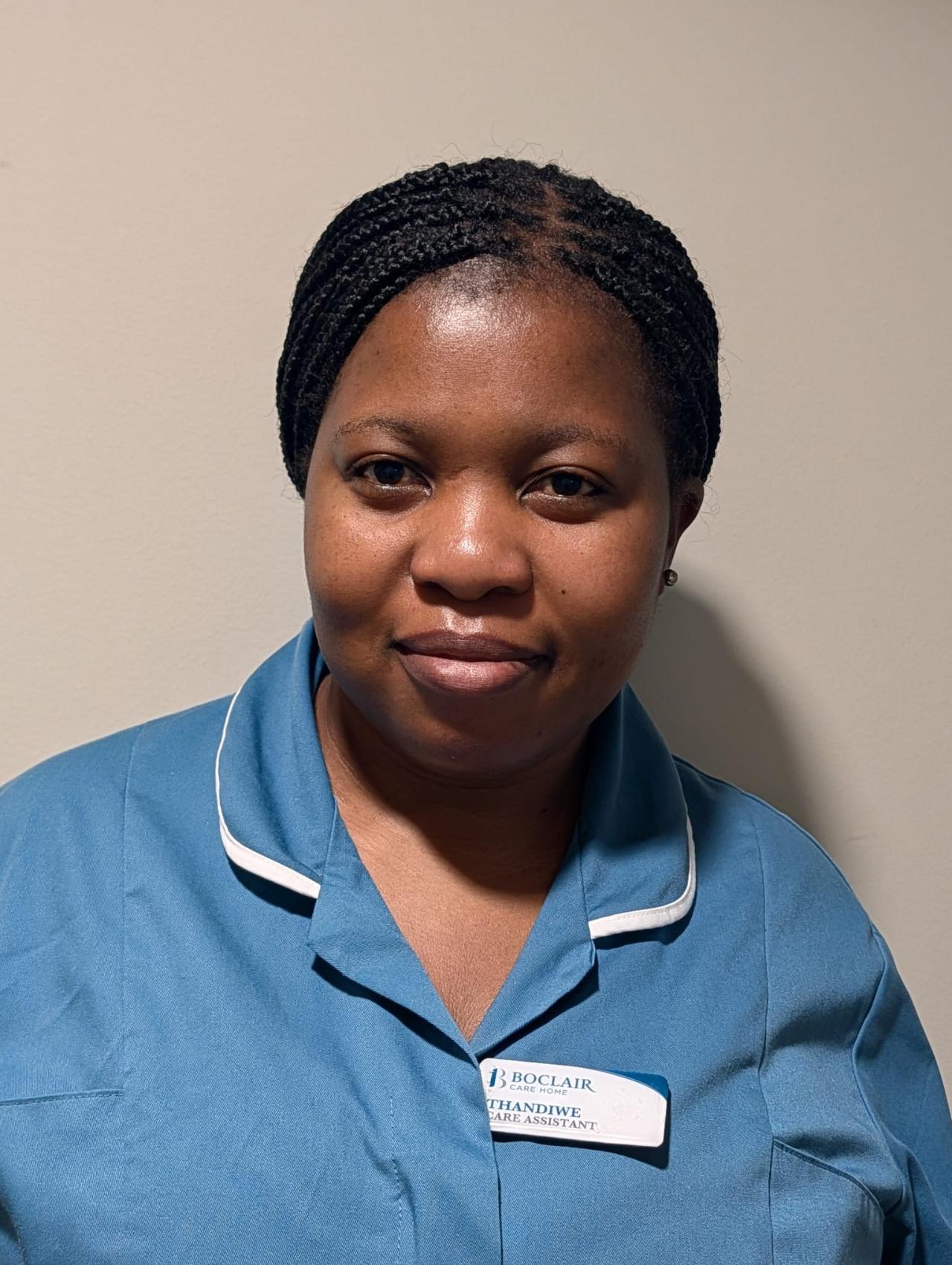 Care assistant with hair tied back wearing a light blue nurses uniform