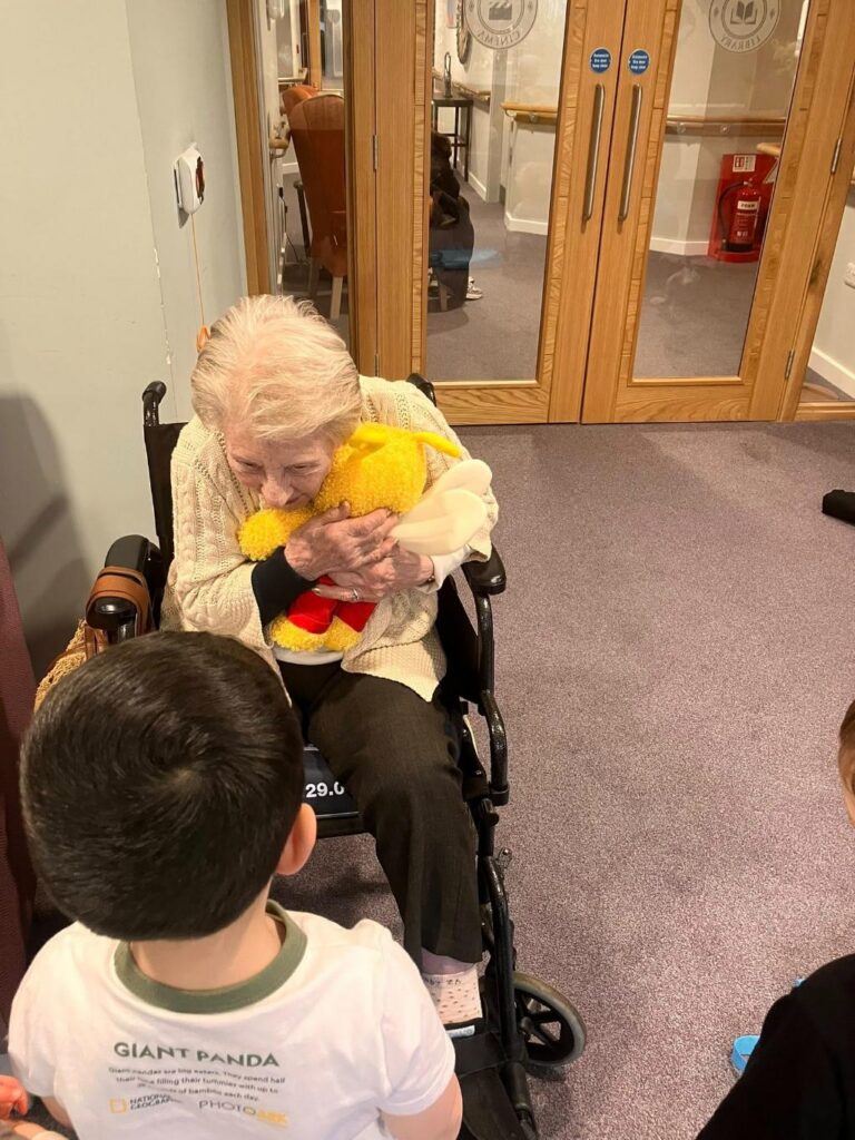 care home resident hugging child's soft toy