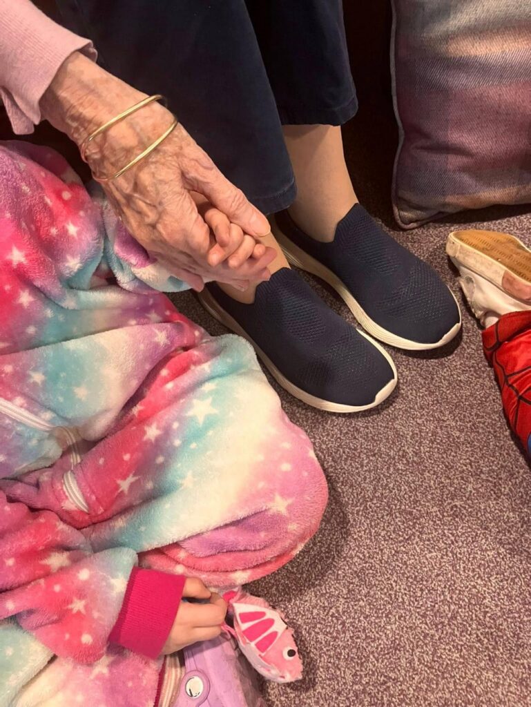 nursery child holding hands with elderly care home resident