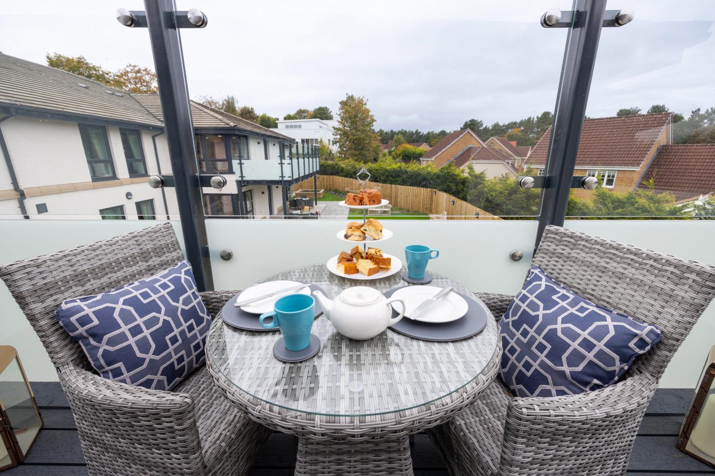 balcony table with afternoon tea and cake on outdoor furniture