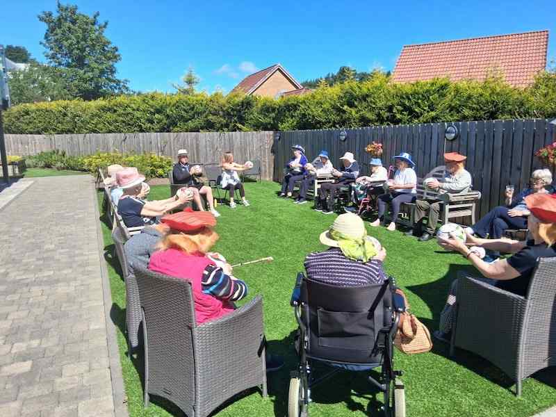 Elderly people sitting outside with football instructor