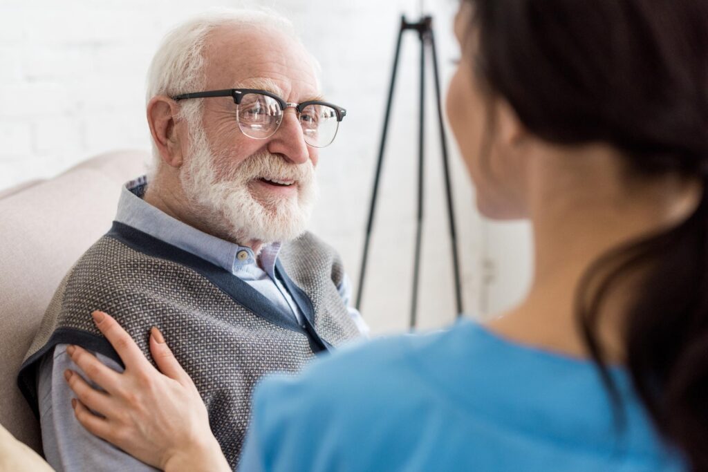 nurse with hand on elderly man's shoulder